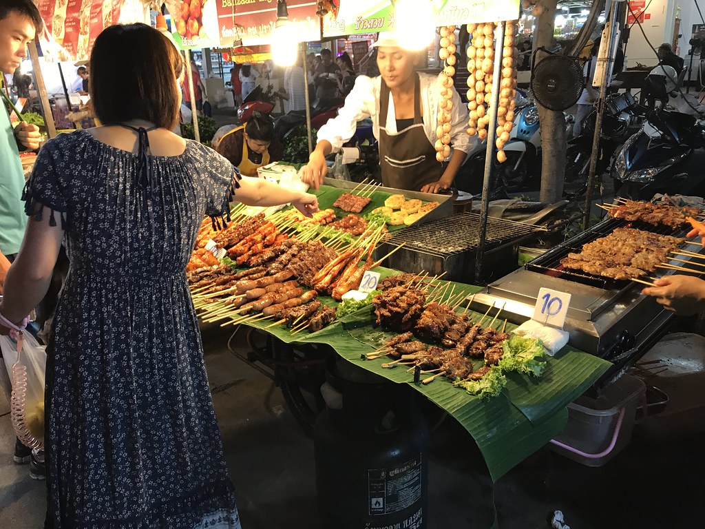 Gruppe af mennesker kigger på mad på et udendørs marked i Phuket