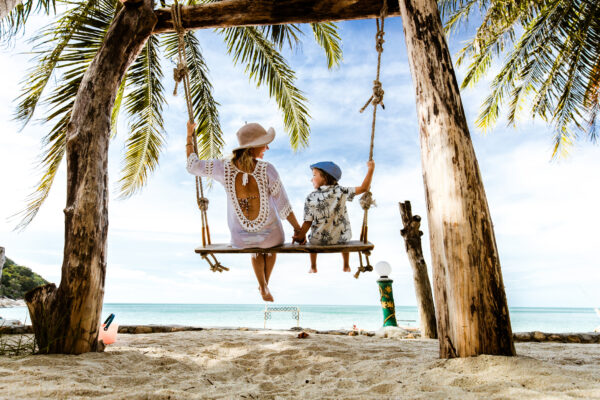 Kvinde og barn på strandferie sidder på en gynge