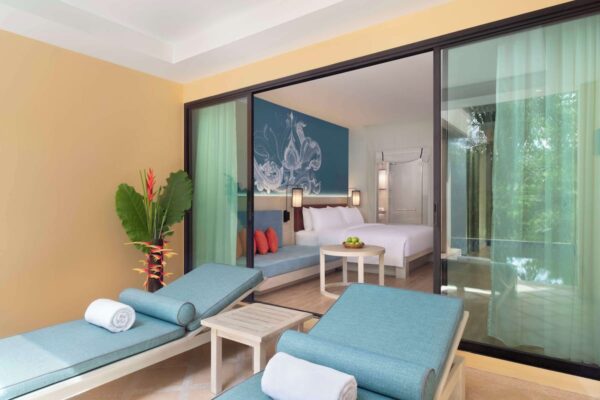 Komfortabel seng, hyggelig loungestole og panorama glasdør i et værelse ved AVANI+ i Koh Lanta Krabi