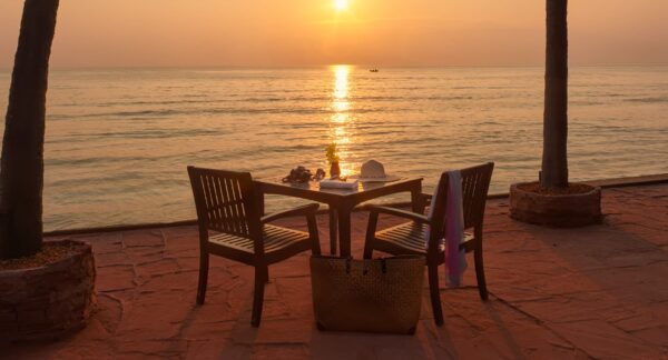 Oceanfront patio på Anantara Hua Hin Resort med bord, stole og en flaske vin