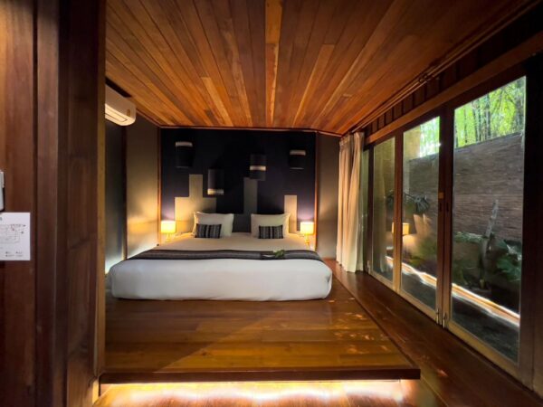 Find et hyggeligt soveværelse på Chiang Saen Boutique Hotel med interiør af trævægge og en behagelig seng.