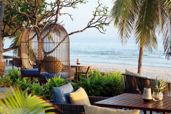 Restaurant ved stranden på Centara Grand Beach Resort, Hua Hin med borde og stole placeret på hvidt sand med udsigt over det blå hav.