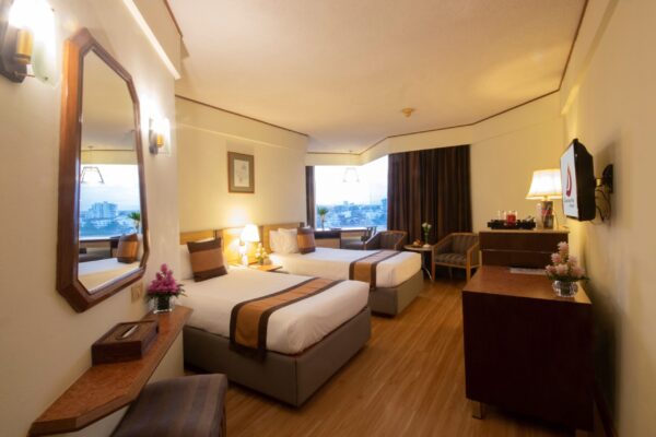 Komfortabelt hotelværelse med senge og udsigt i Chiang Mai på Duangtawan Hotel