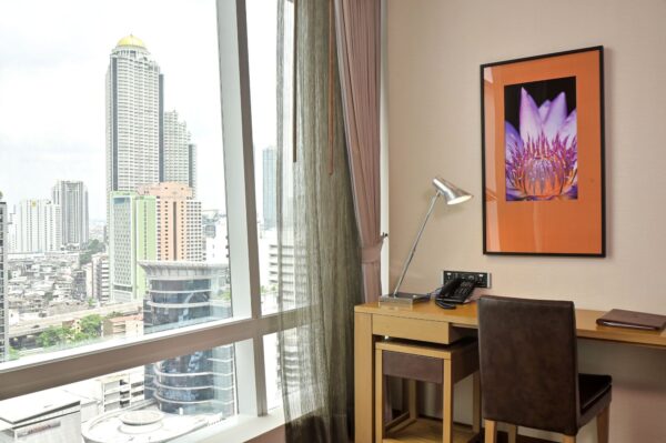 Eastin Grand Hotel Sathorn værelse med skrivebord og udsigt over byen fra vinduet.