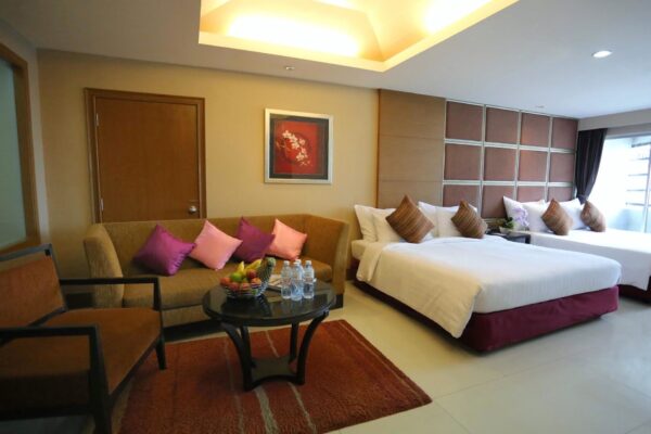 Hotelværelse med senge og sofa på Furama Silom Hotel i Bangkok