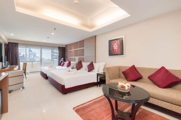 Komfortabelt hotelværelse med senge og sofa i Furama Silom, Bangkok.