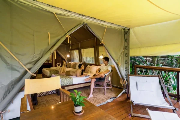 To mennesker sidder inde i et telt på Hintok River Camp og nyder deres eventyrrejse
