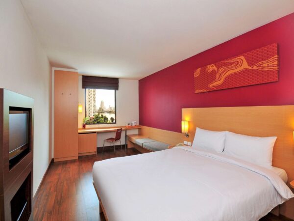 Hotellrom med røde vegger og komfortabel seng på Ibis Riverside i Bangkok