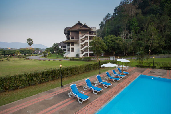 Resort med swimmingpool og liggestole foran bygningen i det gyldne trekant-imperium