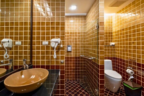 Spa-badeværelse med brune fliser på væggene og brun håndvask
