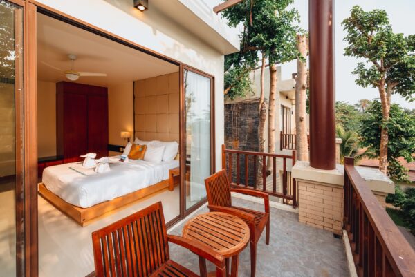 Rummeligt soveværelse med balkon, udstyret med behagelig seng og stole, perfekt til afslapning under spaophold eller feriested. Oplev