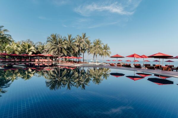 Billed perfekt swimmingpool på KhaoLak Laguna Resort med røde paraplyer og omgivet af tropiske palmer