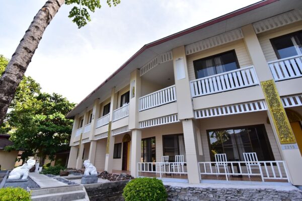 Hvid resortbygning med balkon omgivet af palmer på Koh Hai Fantasy Resort