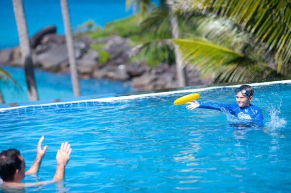  mand der kaster frisbee ved pool på strand resort