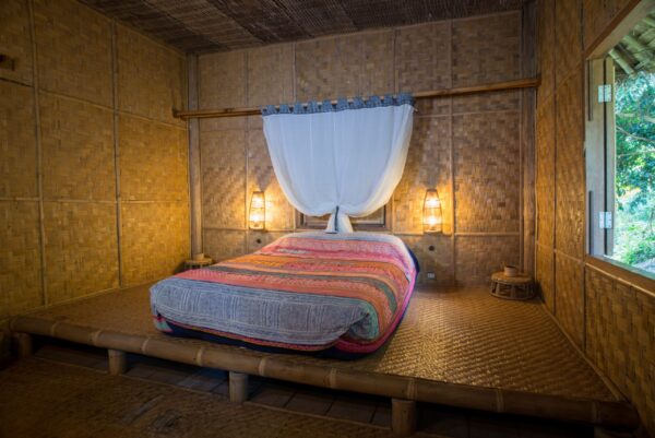 Naturligt designet værelse med bambusvægge og seng på Lanjia Lodge i Chang Rai. Perfekt til dem, der søger autentisk, øko-venligt ophold i