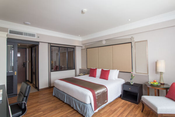 Stilfuldt hotelværelse i Wyndham Bangkok Menam Riverside eller Ramada Plaza med behagelig seng, praktisk skrivebord og komfortabel stol.