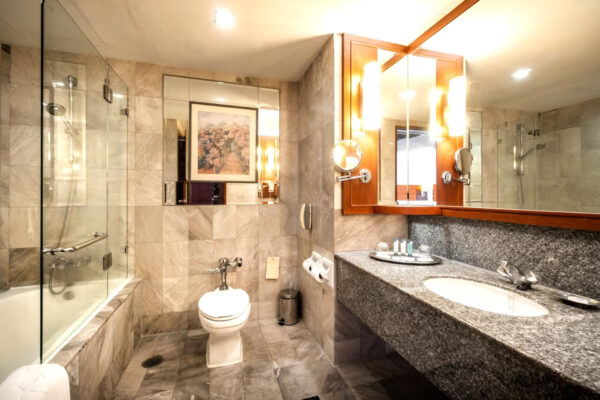 Moderne badeværelsesfaciliteter på Rembrandt Hotel Suites Bangkok med håndvask, toilet og bruser. Perfekt komfort og bekvemmelighed til