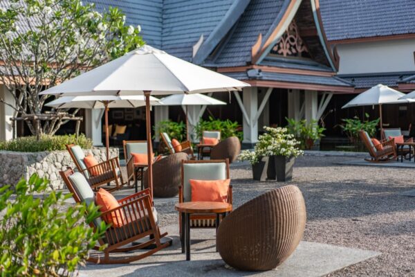 SAii hotel i Laguna Phuket med terrasse, stole og parasoller foran bygningen