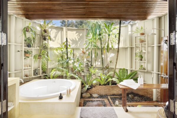 Badeværelse med stort badekar omgivet af grønne planter på SHANTAA resort i Koh Kood