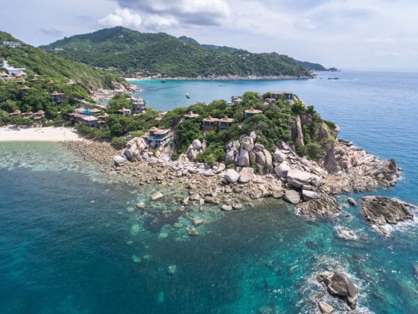 Overhead Sai Daeng Resort på en klippeø i Thailand, der viser frodige grønne områder og klart turkisblåt vand.