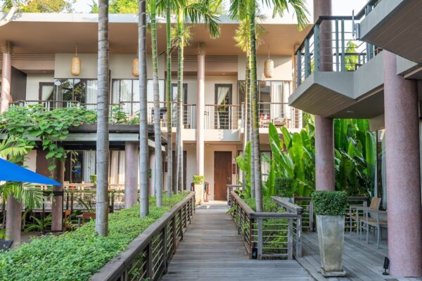 sti til Sai Kaew Beach Resort omgivet af træer med blå paraply