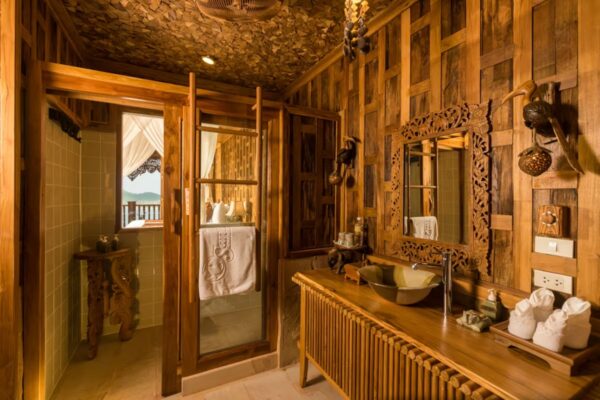 Santhiya Resort Koh Yao Yais luksuriøse træbadeværelse, der viser indviklede træpaneler og en enestående trævask for et autentisk rustikt