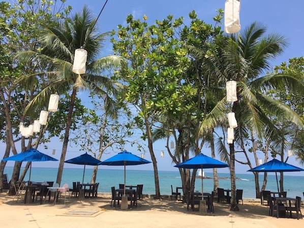 Khao Lak strandrestaurant i Seaview Resort med blå paraplyer og palmer