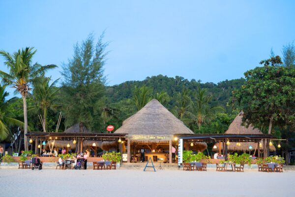 Beachfront restaurant på Southern Lanta Resort med spiseborde arrangeret på sandede kyster.