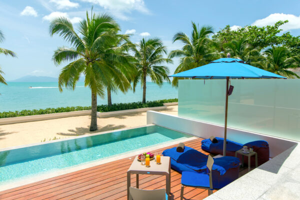 Relax ved en voksne kun swimmingpool med lounge stole og blå paraply på Coast Koh Samui