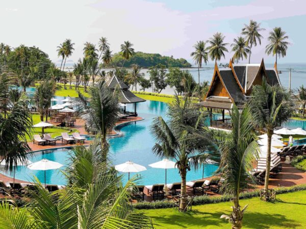 Et luksuriøst boutique-resort i Tubkaak med en stor udendørs swimmingpool omgivet af frodige, tropiske palmer.
