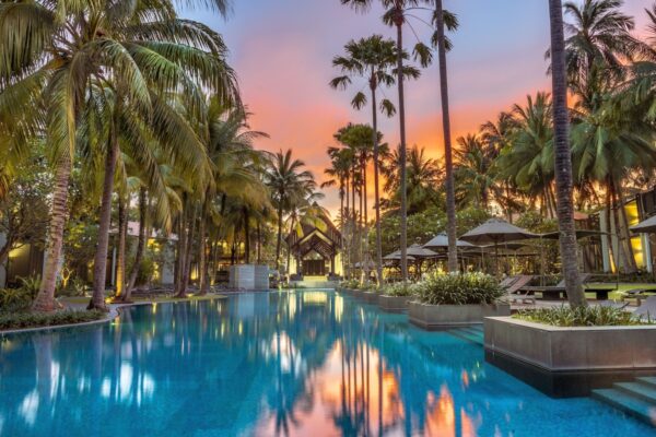 Swimmingpool på Twinpalms resort i Phuket i skumringen med palmer omkring