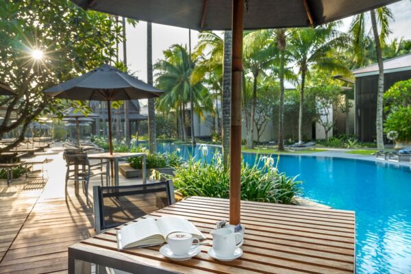 Bord med kaffe og bog ved poolen på Twinpalms Phuket Resort