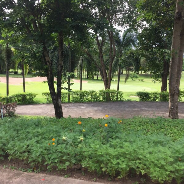 Se det frodige landskab af Hua Hin golfbane, omgivet af grønne træer og buske