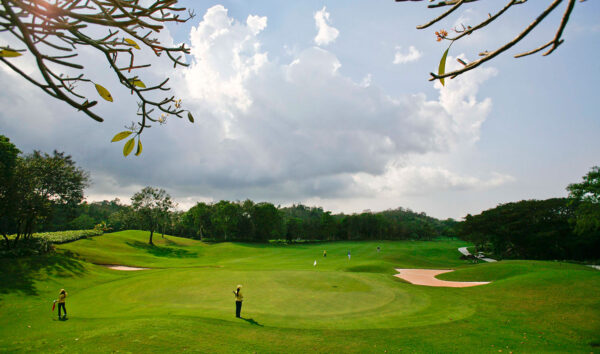 Laem Chabang International Country Club golfbane omgivet af grønne træer under en overskyet himmel
