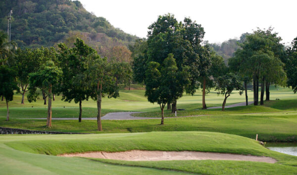 Laem Chabang International Country Club golfbane med masser af træer og en fredelig dam.