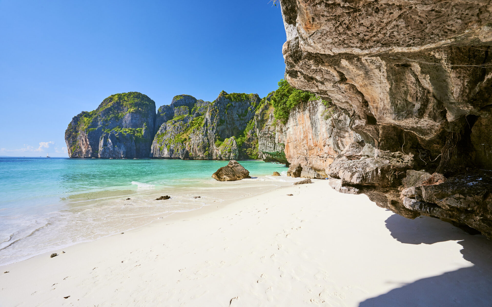 Solrig strand med hvide klipper og gyldent sand i Thailand