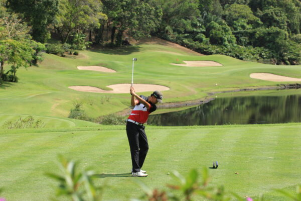 Mand spiller golf på Red Mountain Golf Club i Phuket. Billedet viser en person, der forbereder sig på at svinge køllen, på en grøn og