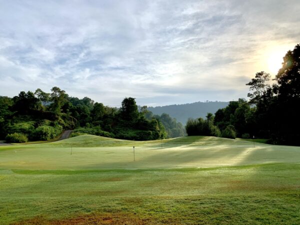 Grøn golfbane med bjerge og træer på Red Mountain Golf Club i Phuket. Ideel til naturelskere.