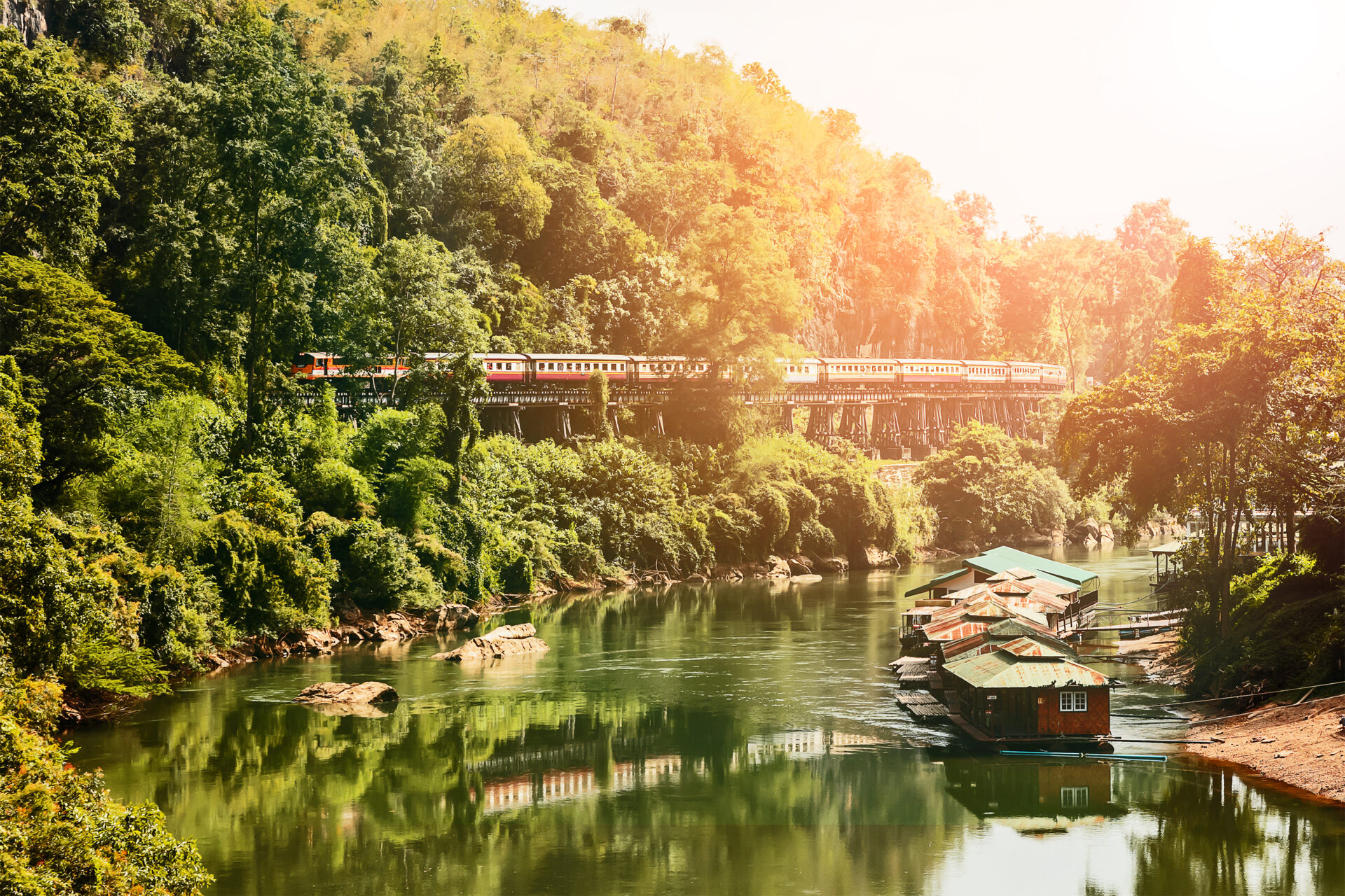 Historisk togrejse gennem frodig skov langs en naturskøn flod i Thailand