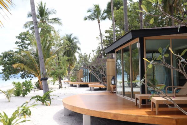 Moderne villaer med glasvægge og træterrasser omgivet af tropiske planter på den lyse sandstrand ved Sivalai Beach Resort.