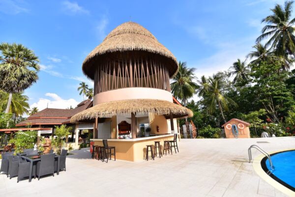 Hyggelig strandbar med stråtag og palmer ved poolen på Sivalai Beach Resort under skyfri himmel på Koh Mook.