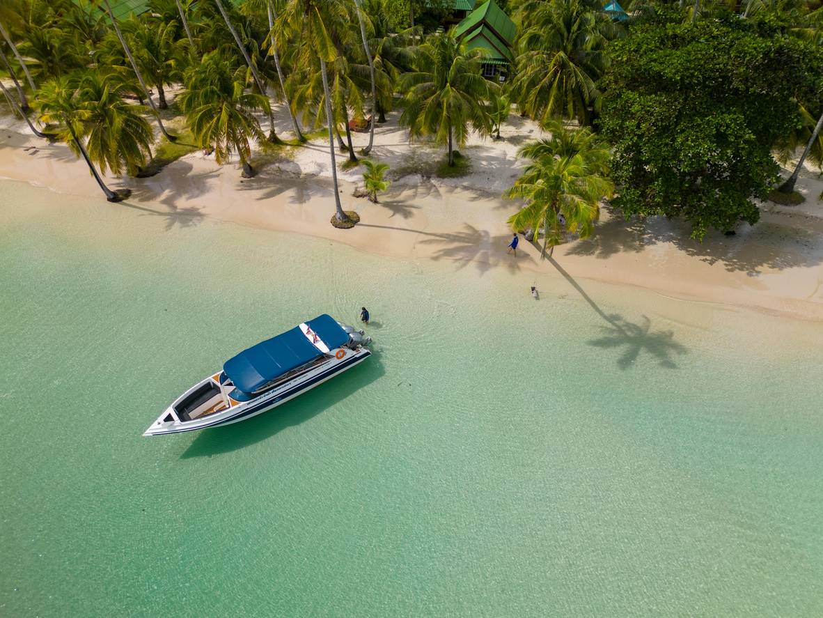 Luft en båd på en sandstrand i Thailand omgivet af palmer