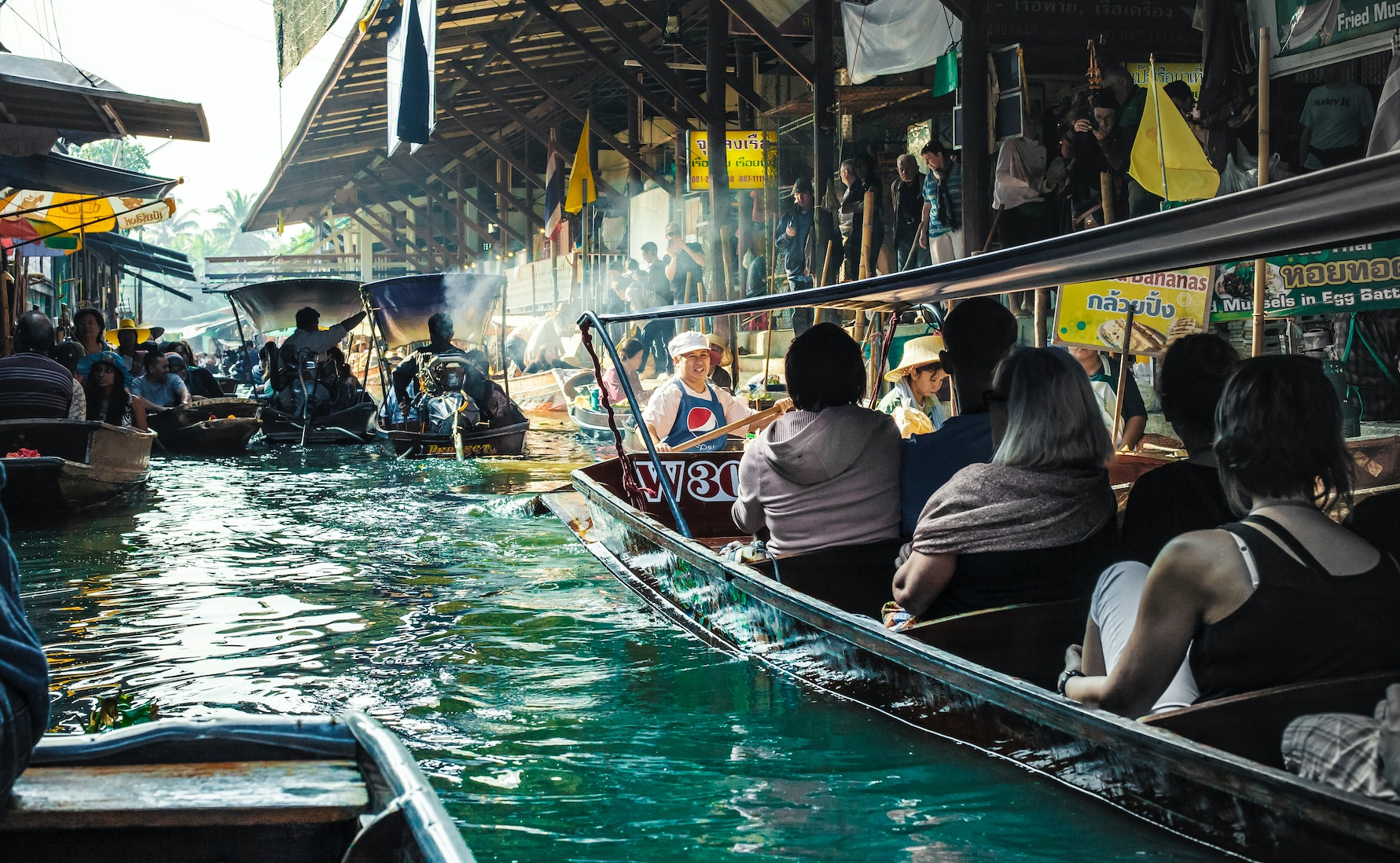 Gruppe af mennesker sejler ned ad en kanal i Thailand i en båd som en del af deres lokale transportoplevelse