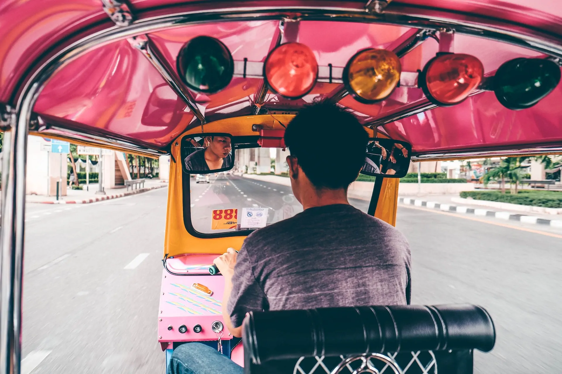 en mand, der kører et lyserødt tuk-tuk i Bangkok, Thailand