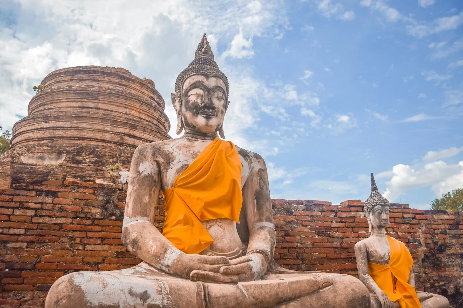 Murstensvæg med to Buddha-statuer i Thailand