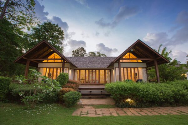 Tropisk ø-hus omgivet af frodig, grøn skog på Koh Mak Island, Thailand. Hus i naturlig indstilling ved tusmørkets start.