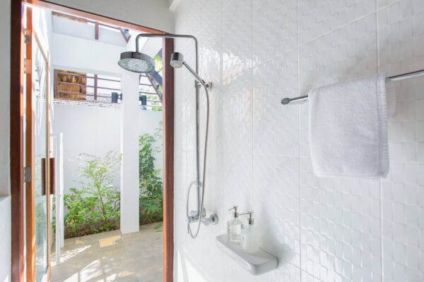 Moderne Mira badeværelse med minimalistisk design. Montra Koh Mak dør åbner op til en smuk, velplejet have. Masser af naturligt lys og plads