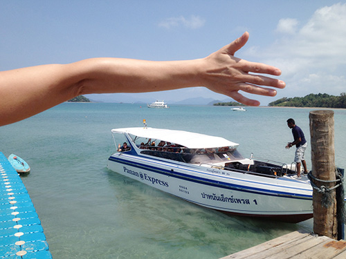 Kvinde rækker hånden ud til både i vandet nær Seavana beach resort Koh Mak