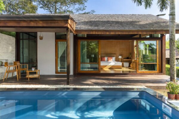Elegant moderne villa med store glasdøre og privat pool i solrige omgivelser på Kreta, afslappet stemning.