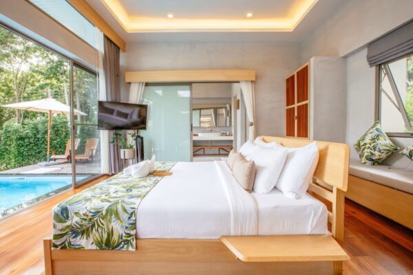 Lyst soveværelse med tropiske tekstiler og udsigt til privat pool og terrasse i eksotiske omgivelser på Bali.